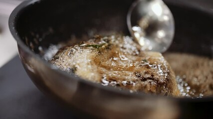 Professional chef cooks meat in a frying pan in a restaurant