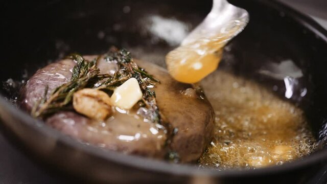 Professional chef cooks meat in a frying pan in a restaurant