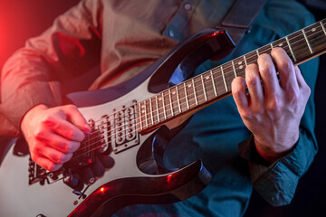 Naklejka na ściany i meble Male hands playing electric guitar. Musician man with black guitar at a rock concert