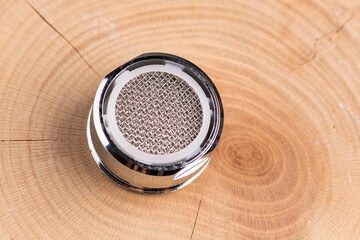 Aerator strainer in faucet isolated on wood from above