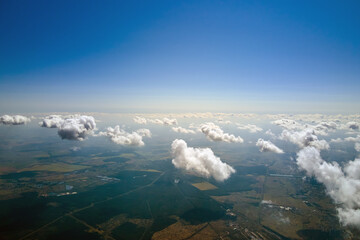 Aerial view from high altitude of earth covered with white puffy cumulus clouds on sunny day
