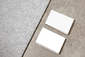 Blank white business cards on rough concrete surface. Mockup for branding identity. Two stacks, to...