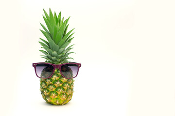 Pineapple in sunglasses on a white background. Ripe juicy fruits in trendy sunglasses on a white...