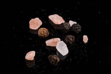 himalayan salt with peppercorns on black background