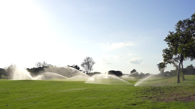 Automatic high-pressure water sprinkler at the golf course watering the grass