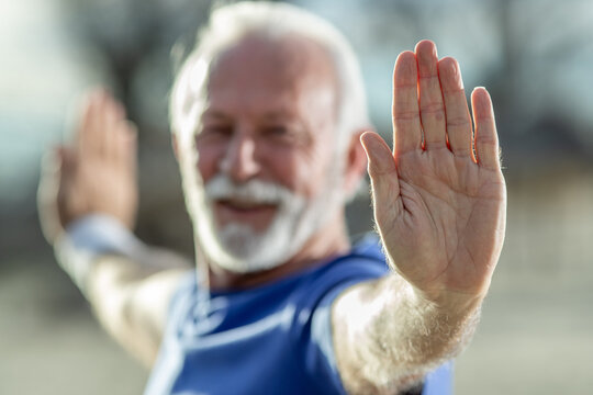 Senior man doing exercise, stretching hands, outdoor
