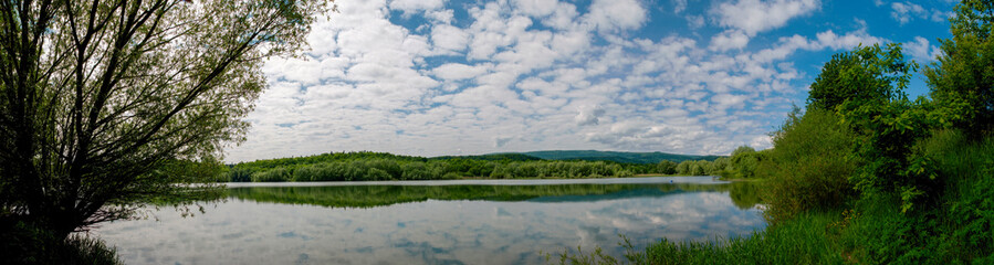 Fototapeta na wymiar Panoramic view of a calm lake on a sunny summer day
