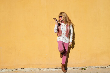 woman with mobile phone isolated on the wall outdoors