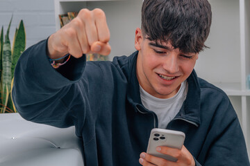 young man looking at mobile phone or cell phone with expression of success and joy