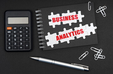On the table is a calculator, a pen and a notebook with the inscription - BUSINESS ANALYTICS