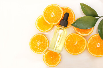 Beauty concept of Vitamin C serum in cosmetic bottle with dropper and slices of orange fruit on white background.