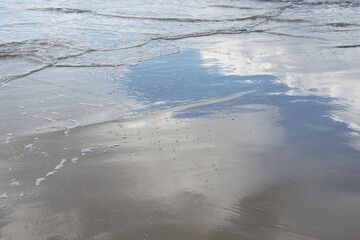reflection of clouds in sea water on the sandy beach mediterranean coast background