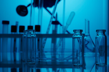Empty lab glassware. Medical chemical lab with blue light background. Photo is taken in clinic laboratory with clean glasses on a table. Small glass vials and flasks without fluids on a chemical desk