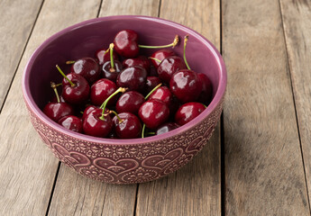 Red cherries on a bowl over wooden table