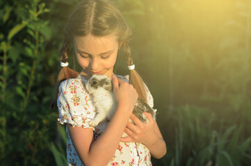 The child hugs a little rabbit. Easter symbol. Friendship between child and animal.