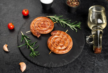 grilled sausages in the form of a spiral on skewers on a stone background