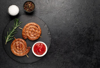 grilled sausages in the form of a spiral on skewers on a stone background  with copy space for your text