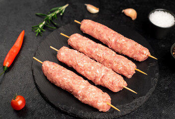 raw lula kebab on skewers with spices on a stone background