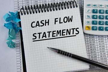 CASH FLOW STATEMENTS - words in a white notepad on the background of a calculator and a pen