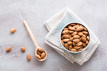 Fresh peeled almonds in a wooden spoon and in a bowl nearby on a light background. A source of vitamins and oils. Organic food. Top view