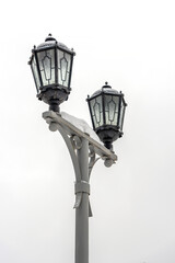 Fototapeta na wymiar Vintage lamppost covered with white snow on a gray sky.
