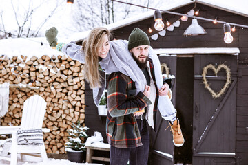 Fototapeta na wymiar couple of young woman and man having fun in courtyard of decorated suburban house in winter, concept of Christmas and New Year vacation on farm, family love and support, Valentines Day celebration