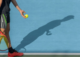 Young tennis player with ball and racket performs serve while playing on red clay court. Tennis...