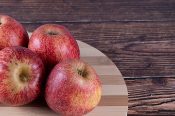 Tasty apples (Malus domestica, scientific name in Latin) on a bamboo board, table in rustic wood. Selective focus.