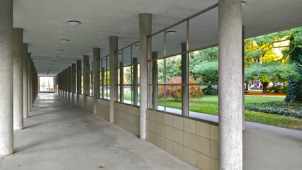 Empty colonnade in the park in spa city. The colonnade is white with pillars and windows without glass.