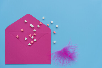 pink envelope on a blue background. Classic colors for a Valentine's Day card. small multi-colored hearts fly from the open envelope. The concept of congratulations on Valentine's Day. love and