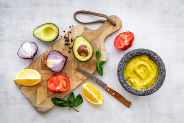 Mexican spicy guacamole avocado dip in mortar with ingredients