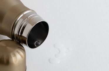 Transparent drop of clean water close-up in the neck of metal thermos on white background