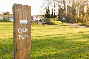 Cycle track sign on a wooden post giving directions to cyclist outdoors