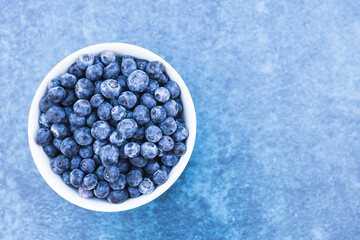 Bowl of fresh blueberries isolated on blue background