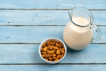 almond milk in a glass carafe on a blue wooden background, space for text