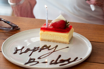 birthday candle on top of cheesecake cake with strawberry on it