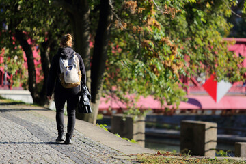 Kobieta z plecakiem spaceruje w parku we Wrocławiu.