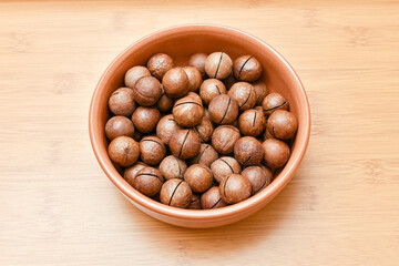 macadamia nuts in brown cup on wooden background