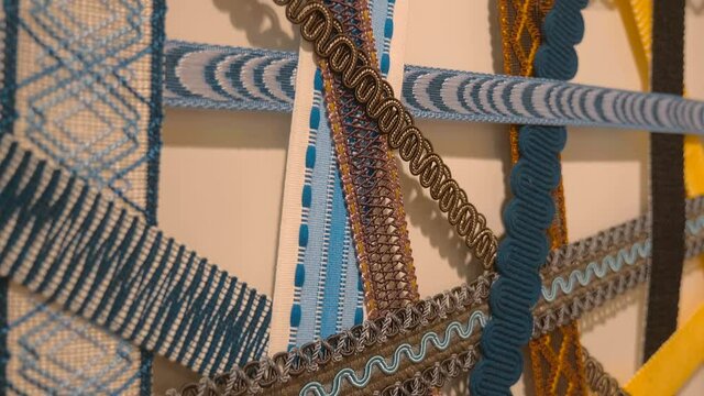 New colorful samples of decorative braid for window curtains are located with each other for better comparison and selection of the suitable. Shot in motion. Closeup