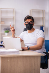 Young male student employee working at workplace during pandemic