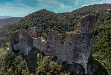 Aerial view of under restoration medieval Reviste castle above the Hron (Garam) river in Slovakia with donjon, circular gate tower, ruined gothic palace blue cloudy sky 