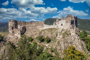 Aerial summer view of Sasov castle in Slovakia above the Hron river with circular donjon tower and partially restored walls on a hilltop