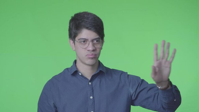 Hombre negando y rechazando con su expreci&oacute;n corporal y fondo verde