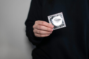 Woman hands holding condom package. A condom use to reduce the probability of pregnancy or sexually...