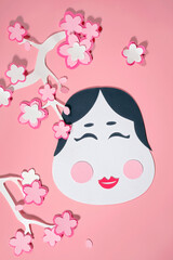 Cute Setsubun paper-craft with Okame mask and sakura blossom branch. Background for traditional japanese festival, Bean throwing Day