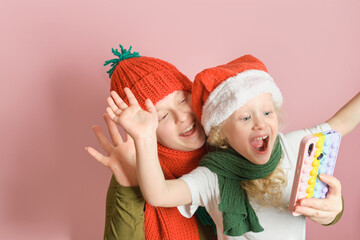 Mother and daughter in hats and scarfs having video call on pink background
