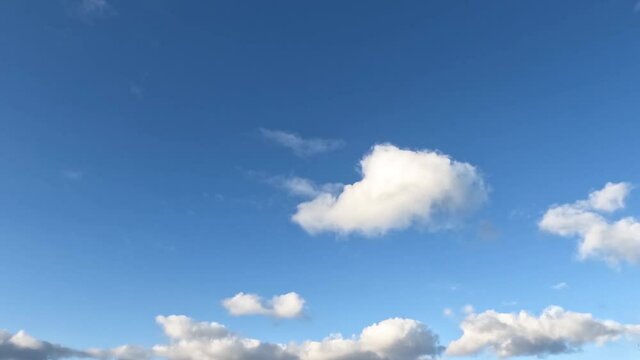 Beautiful clouds float across the sky, a plane flies in the distance.