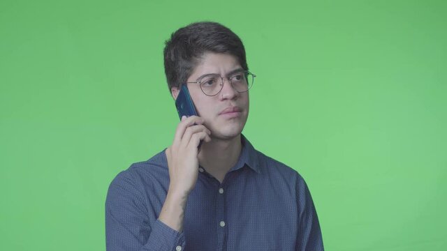 Hombre latino recibiendo llamada telef&oacute;nica con fondo verde