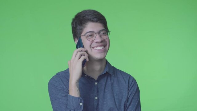 Hombre latino recibiendo llamada telef&oacute;nica con fondo verde