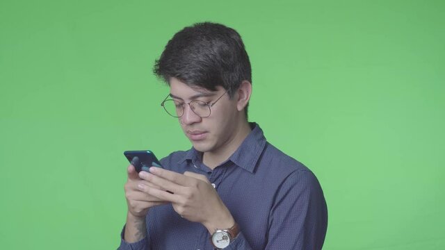 Hombre latino usando el telefono celular con fondo verde